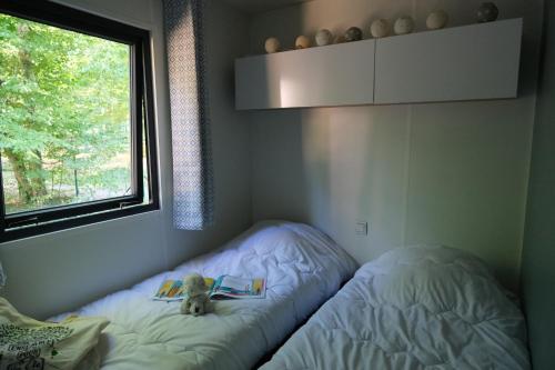 ein ausgestopftes Tier auf einem Bett in einem Zimmer mit Fenster in der Unterkunft Camping Saint Michel in Courtils