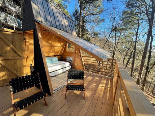 eine Hütte mit zwei Stühlen und einer Couch auf einer Terrasse in der Unterkunft Loblolly Pines Adventure Aframe #2 in Eureka Springs