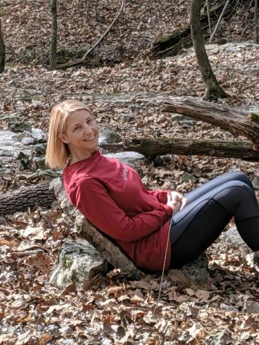 a woman sitting on a rock in the woods at Loblolly Pines Adventure Aframe #2 in Eureka Springs