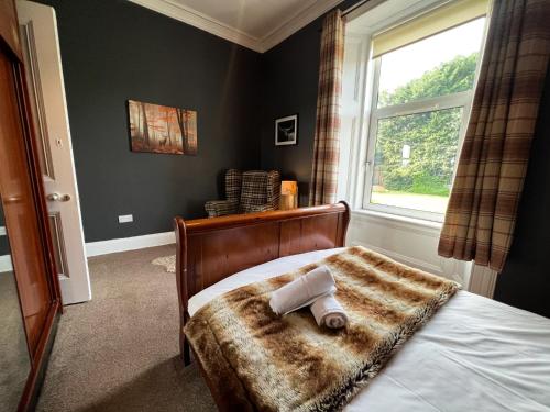 Un dormitorio con una cama con una toalla. en A Spacious Flat with Character - Private Car Space en Paisley