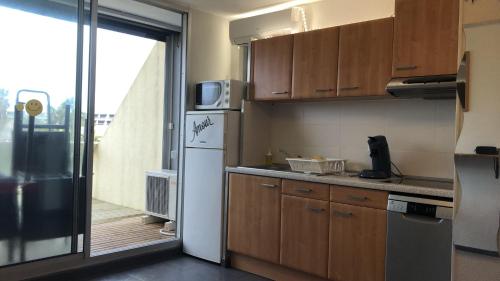 a kitchen with a refrigerator and a door to a balcony at Studio Village Naturiste vue mer HELIOPOLIS C in Cap d'Agde