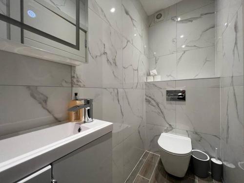 uma casa de banho branca com um WC e um lavatório em Star London Finchley Road 1-Bed Hideaway em Londres