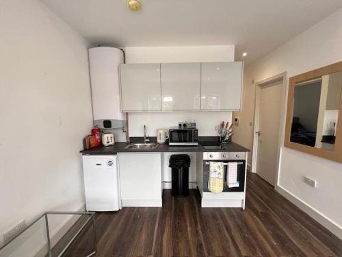 uma cozinha com armários brancos e uma bancada em Star London Finchley Road 1-Bed Hideaway em Londres