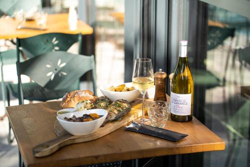 a table with a bottle of wine and bowls of food at Logis NIMOTEL Hôtel Cosy in Nîmes