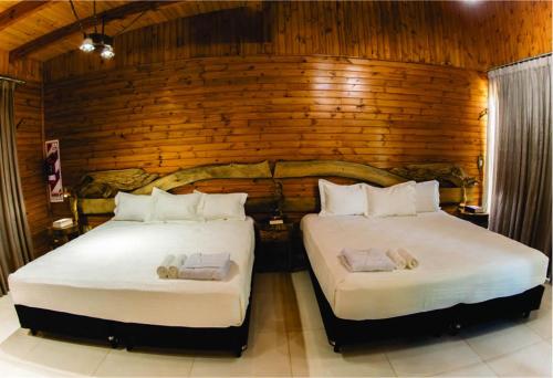 2 camas en una habitación con paredes de madera en Tupa Lodge en Puerto Iguazú