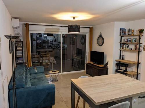 un salon avec un canapé bleu et une table dans l'établissement Appartement douillet avec jardin pour 4 personnes, à Cauro