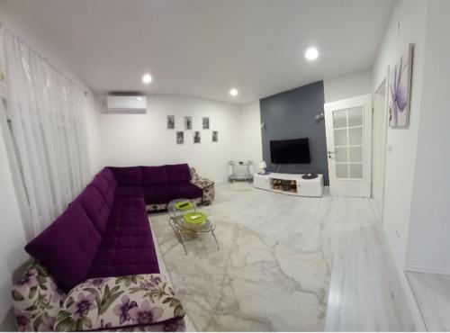 een woonkamer met een paarse bank en een tv bij Aine Apartman - Old Bridge in Mostar