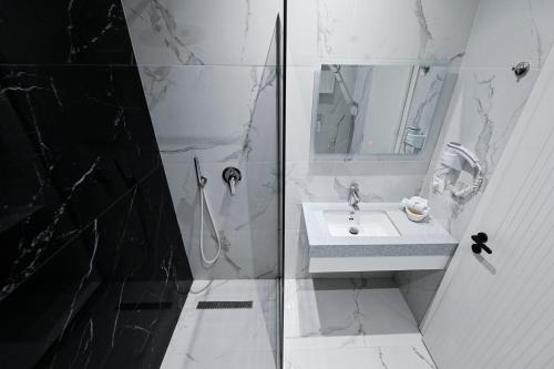 a white bathroom with a sink and a shower at Royal G Max in Golem