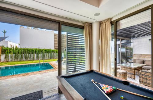 a pool table in a room with a swimming pool at Theme - Taghazout - Luxury villa - 10 Px in Taghazout