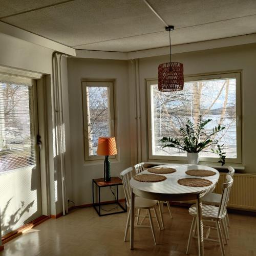 a dining room with a table and chairs and windows at Sataman helmi in Savonlinna