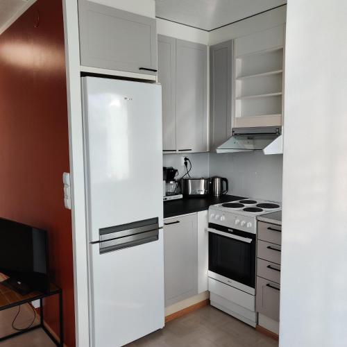 uma cozinha com armários brancos e um frigorífico branco em Sataman helmi em Savonlinna