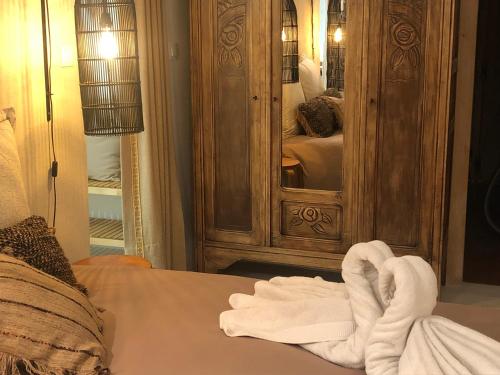 une serviette assise sur un lit devant un miroir dans l'établissement L' îlot des îles, à Cuxac-dʼAude