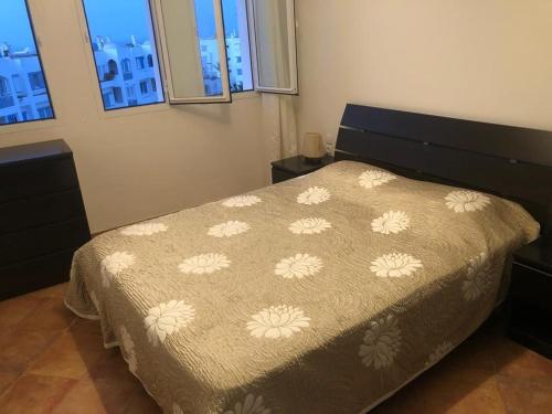 um quarto com uma cama com uma colcha com flores em Un bel appartement à Jawhara Smir, Marina Smir em Fnideq