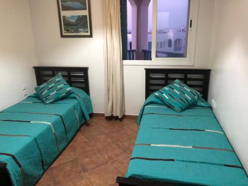 Duas camas num quarto com uma janela em Un bel appartement à Jawhara Smir, Marina Smir em Fnideq