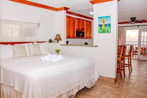 a bedroom with a large white bed and a kitchen at Mayan Princess Hotel in San Pedro