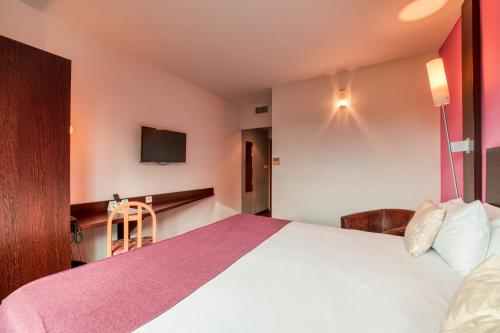 a hotel room with a large bed and a tv at Logis NIMOTEL Hôtel Cosy in Nîmes