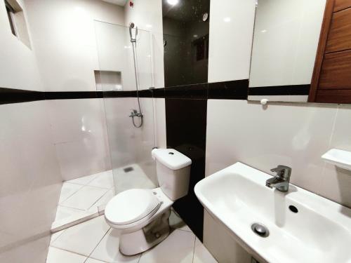 a white bathroom with a toilet and a sink at Executive Tulip Apartelle in Davao City