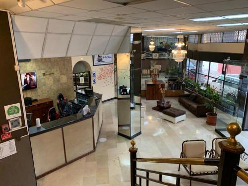 a large room with a lobby with a counter and a living room at Hotel De Las Flores in Ambato