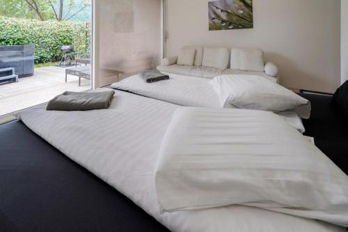 two large white beds in a room at The Glass House & SPA in Caslano