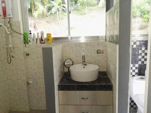 a bathroom with a sink and a toilet and a window at Romytt White House in Virac