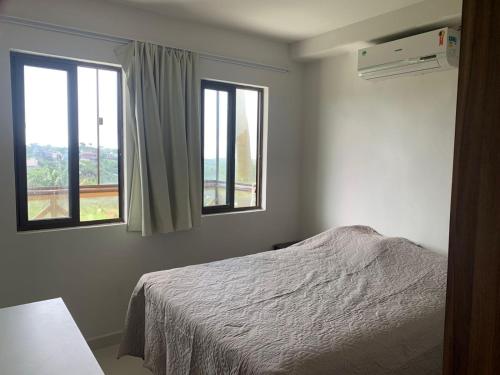 a bedroom with a bed and two windows at Cond. Sonhos da Serra in Bananeiras