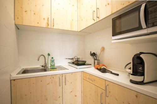 una cucina con armadi in legno, lavandino e forno a microonde di Gemütliches & Modernes Apartment a Coblenza