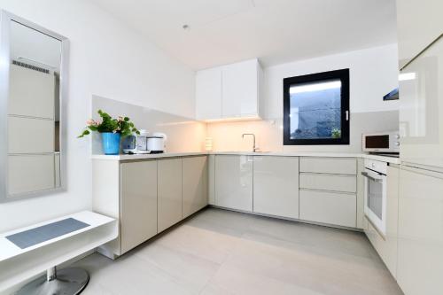 a white kitchen with white cabinets and a window at Sans Souci 1 in Caslano