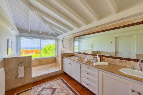 een badkamer met 2 wastafels en een groot raam bij Holiday Villa 12 in Rambaud