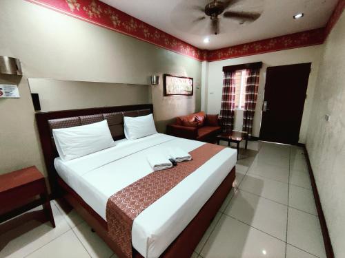a bedroom with a large bed and a living room at Executive Tulip Apartelle in Davao City