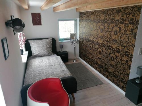 a bedroom with a bed and a red chair at Zum Pfarrberg in Meerane