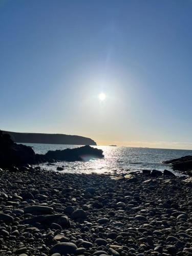 a rocky beach with the sun setting over the water at Beaufighter in Haverfordwest