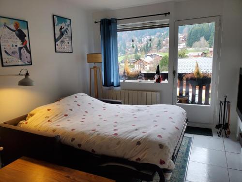 ein Schlafzimmer mit einem Bett und einem großen Fenster in der Unterkunft Studio avec petit balcon et cheminée - Grand Massif in Les Carroz d'Araches