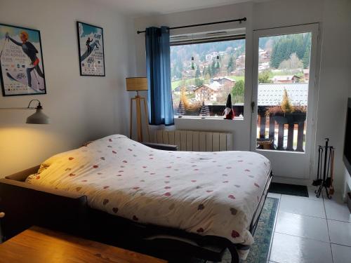 une chambre avec un lit et une grande fenêtre dans l'établissement Studio avec petit balcon et cheminée - Grand Massif, aux Carroz d'Arâches