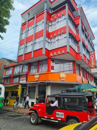 a red jeep parked in front of a building at Hotel las Corocoras del llano in Villavicencio