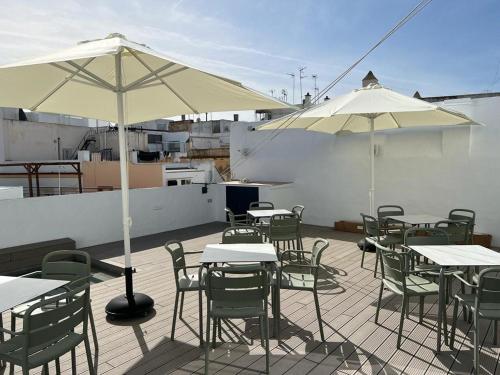 a patio with tables and chairs and white umbrellas at Soho Boutique Columela in Cádiz