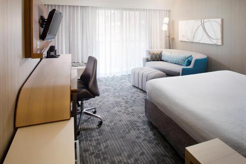 Courtyard by Marriott Richmond Airport في ساندستون: غرفة فندقية بسرير ومكتب مع تلفزيون