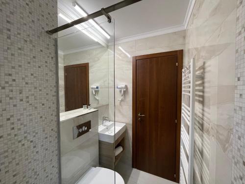 a bathroom with a toilet and a glass shower at PENSIUNEA SKY HUB in Arieşeni