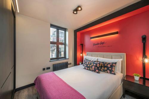 a bedroom with a bed with a red wall at The Influencer Suite - Soho - by Frankie Says in London
