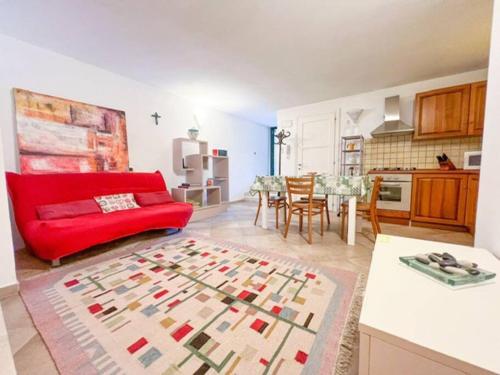 a living room with a red couch and a kitchen at Hibryd: in centro, a due passi dal mare in Oristano