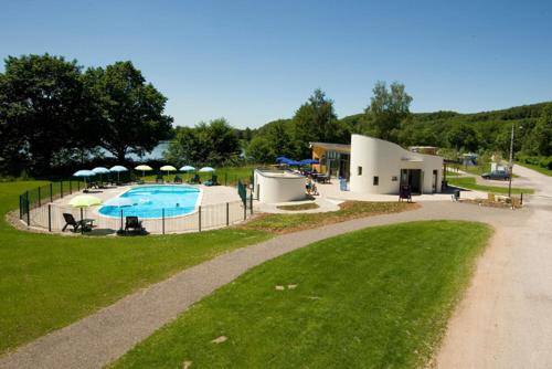 un immeuble avec piscine à côté d'un parc dans l'établissement Camping Les Ballastières - Vosges du Sud, à Champagney