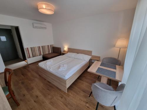 a small room with a bed and a table and chairs at Ádám Apartmanház in Siófok