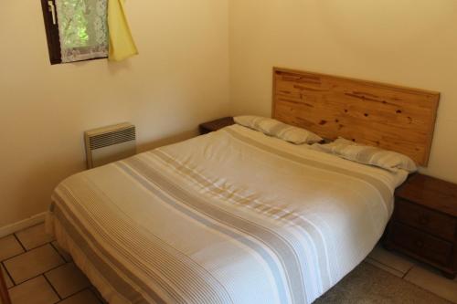 une chambre avec un lit blanc avec une tête de lit en bois dans l'établissement Genevrier Cottage, à Huelgoat