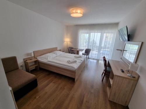 1 dormitorio con cama, escritorio y silla en Ádám Apartmanház, en Siófok