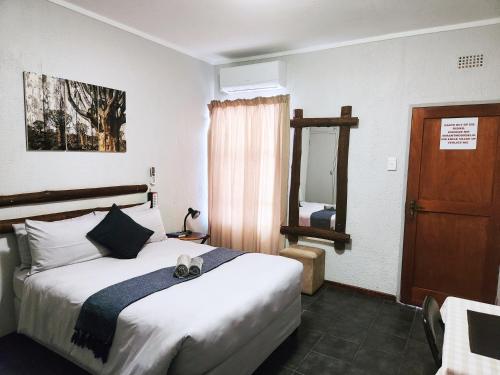 a hotel room with a bed and a mirror at Tramonto Lodge in Upington