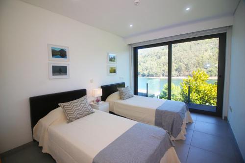 a bedroom with two beds and a large window at Apartamento Javali - Casas Barca do Rio by Gerês Casas in Geres
