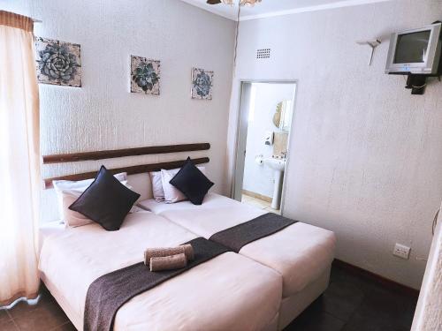 a bedroom with a large white bed with black pillows at Tramonto Lodge in Upington