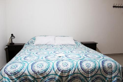 1 dormitorio con 1 cama con edredón azul y blanco en Casa Sirius, en San Pedro de Atacama