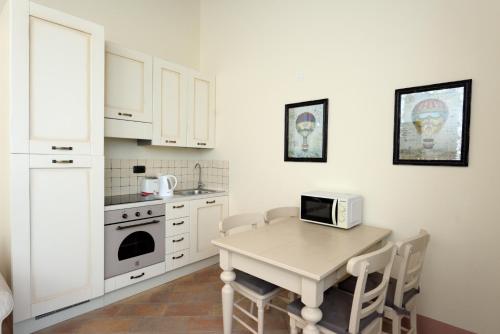 a white kitchen with a table and a microwave at Appartamento Limone in Chianni