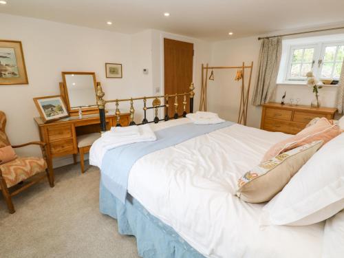 a bedroom with a large white bed and a desk at Gilly Skyber in Helston