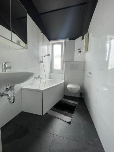 a bathroom with a sink and a tub and a toilet at Joanna Apartment - MA Käfertal 1 in Mannheim